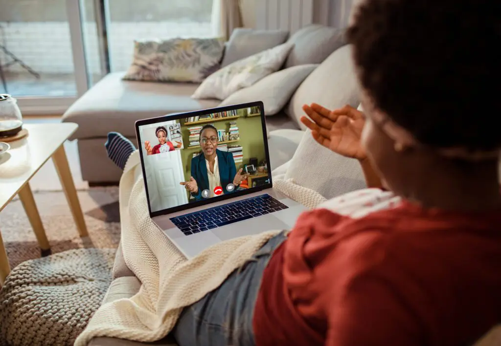 Young woman talking to her therapist online Young woman laying on sofa talks to her online therapist