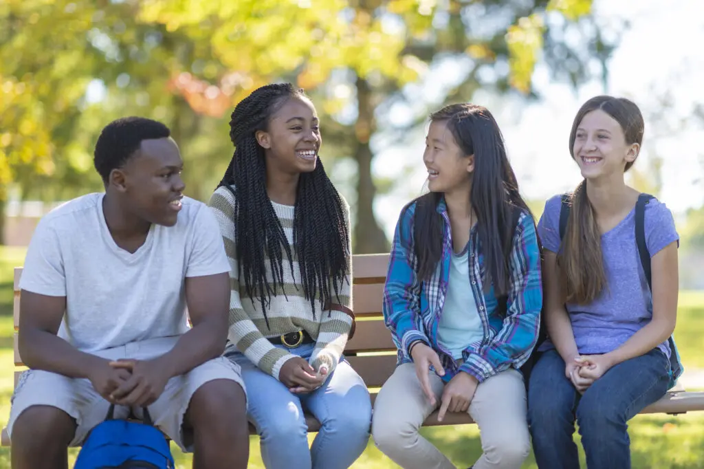 A group of adolescents sitting on a park bench