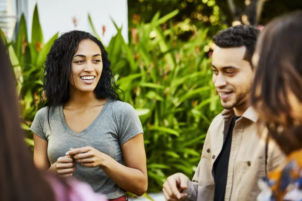 A group of diverse adults sit together chatting outdoors