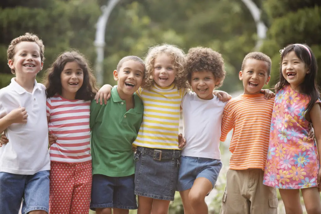 A group of children smile and hug as they play in the park