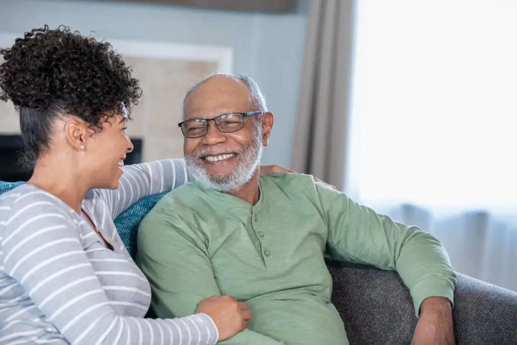 A woman wraps her arm around her elderly father as they smile together